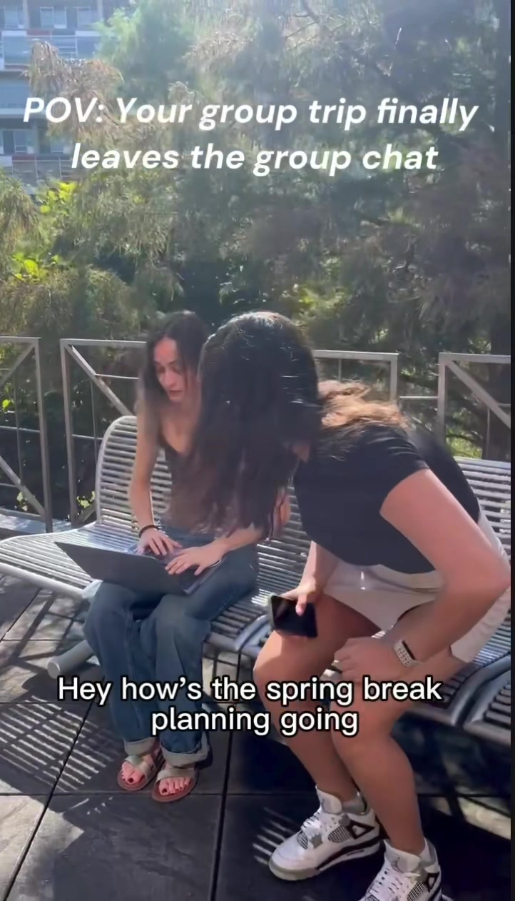 Two friends on a bench, one planning Spring Break on a laptop. Watch the video on TikTok.